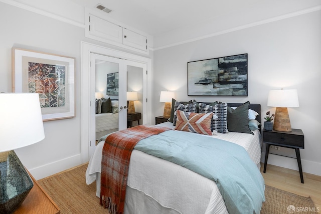 bedroom featuring visible vents, baseboards, and light wood finished floors