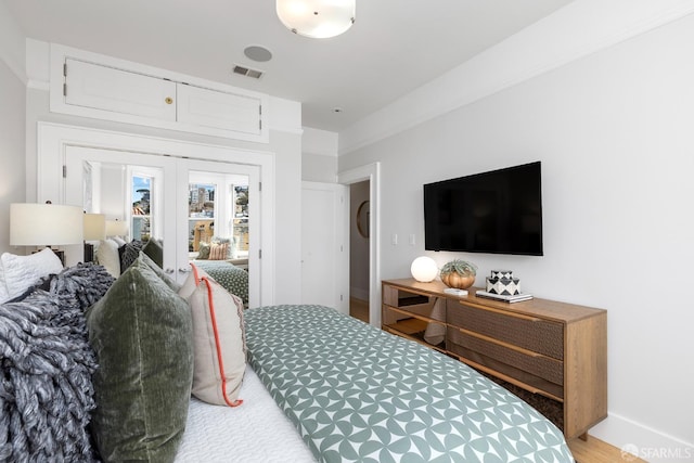 bedroom with wood finished floors, french doors, visible vents, and baseboards