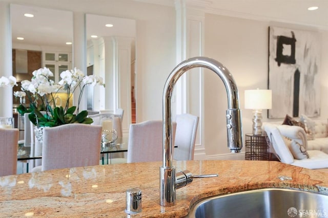 interior details featuring light stone countertops, ornamental molding, and sink