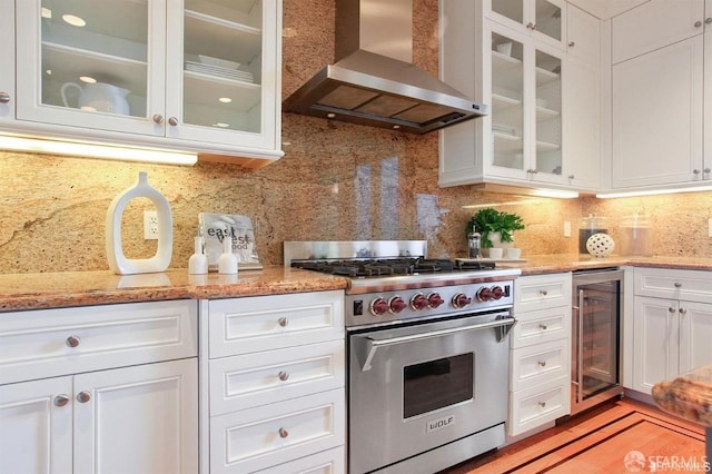 kitchen featuring white cabinetry, premium range, beverage cooler, wall chimney range hood, and decorative backsplash