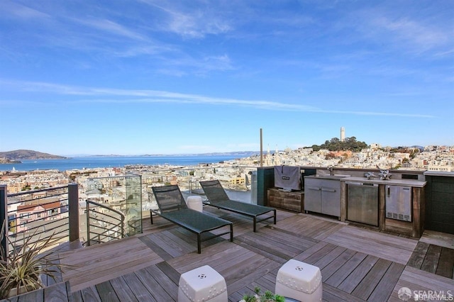 wooden terrace featuring a water view, exterior kitchen, and sink