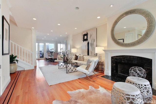 living room featuring wood-type flooring, crown molding, and a premium fireplace