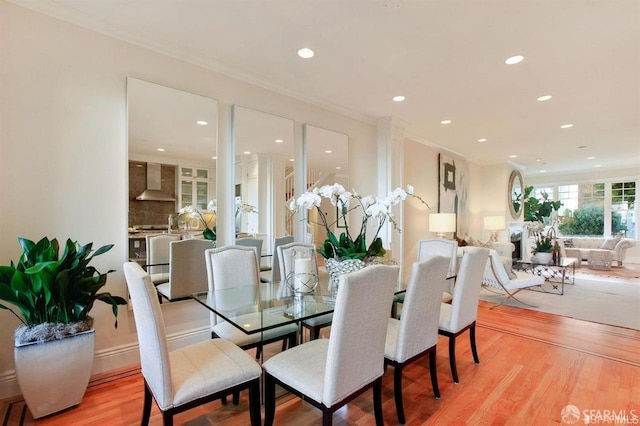 dining space with light wood-type flooring and crown molding