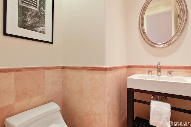 bathroom with vanity, toilet, and tile walls