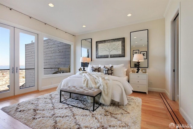 bedroom featuring access to outside, crown molding, french doors, and light hardwood / wood-style floors