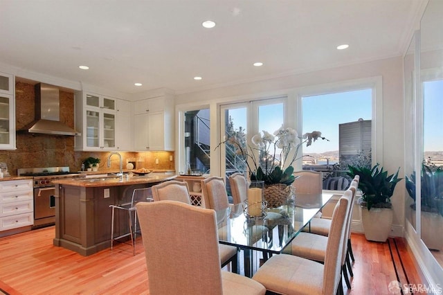 dining area with light hardwood / wood-style floors, crown molding, and sink