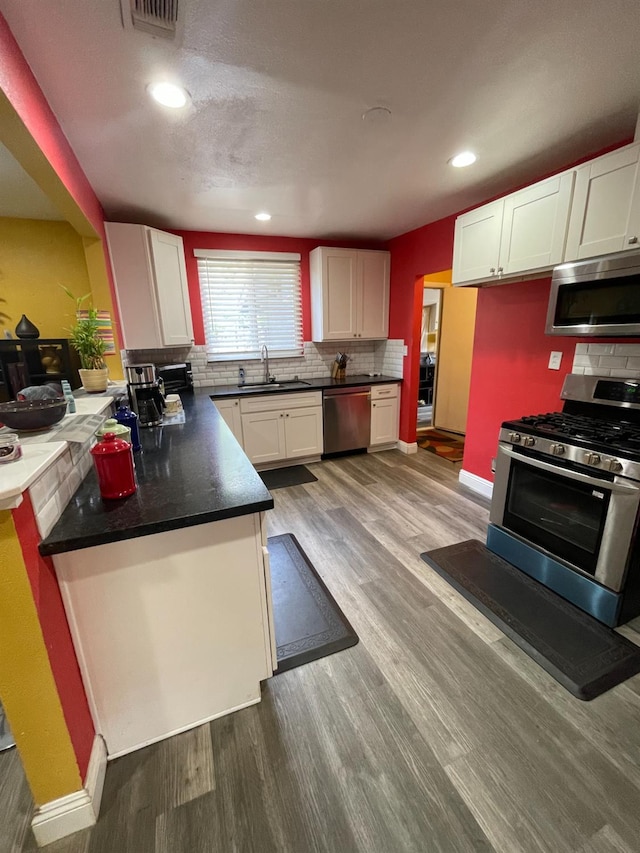 3740 26th Ave, Sacramento, CA 95820 - kitchen with stainless steel appliances, backsplash, white cabinets, wood finished floors, and recessed lighting