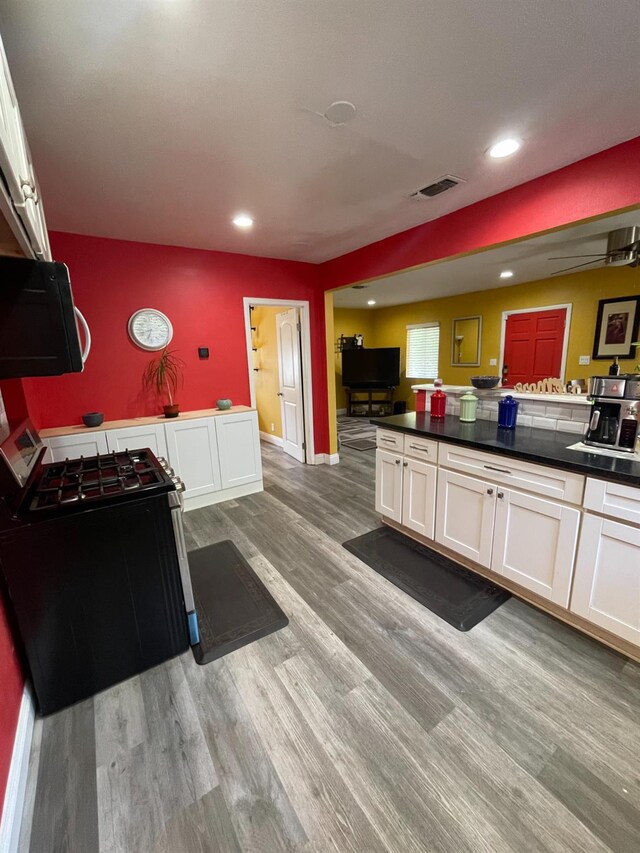 3740 26th Ave, Sacramento, CA 95820 - kitchen with gas range oven, white cabinets, light wood-style flooring, dark countertops, and recessed lighting