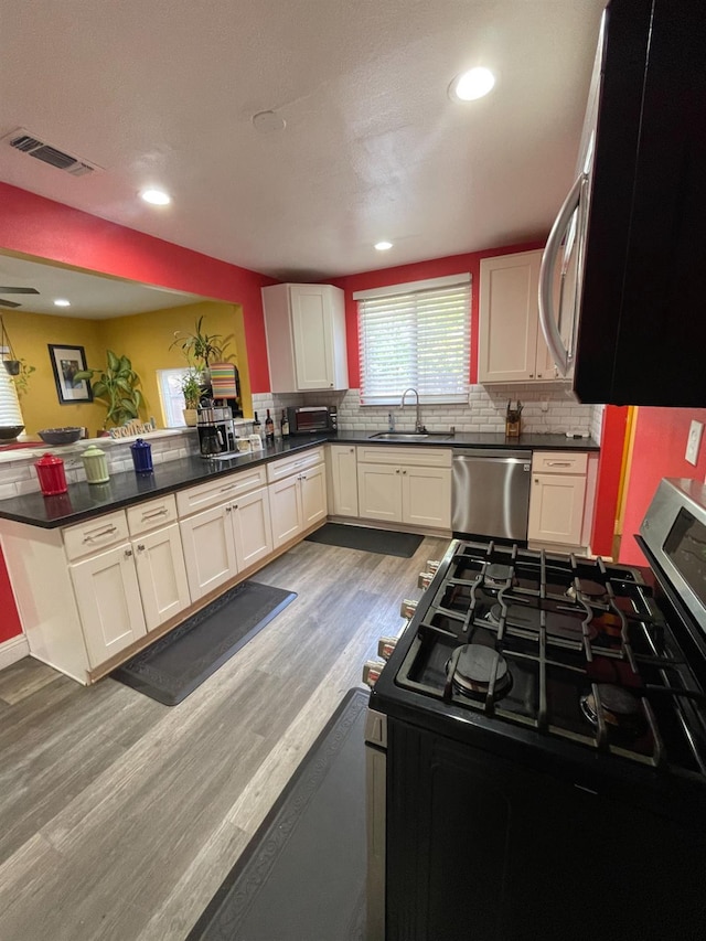 3740 26th Ave, Sacramento, CA 95820 - kitchen featuring stainless steel appliances, tasteful backsplash, light wood-type flooring, dark countertops, and recessed lighting