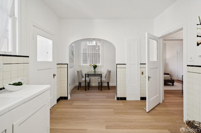 1063-1065 Sanchez St, San Francisco, CA 94114 - hallway featuring arched walkways, light wood-style flooring, wainscoting, and tile walls