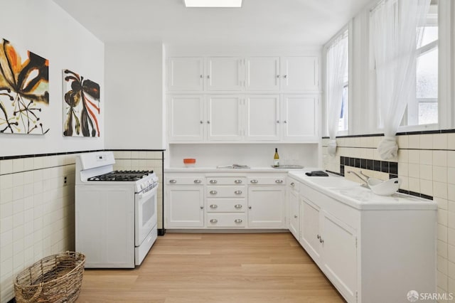 1063-1065 Sanchez St, San Francisco, CA 94114 - kitchen with white gas range, tile walls, white cabinets, light countertops, and light wood-style flooring