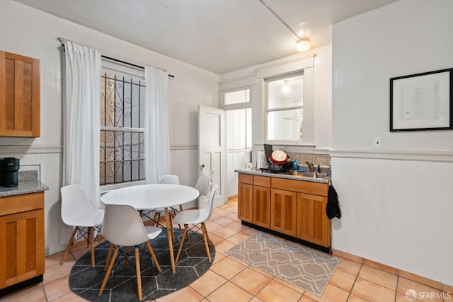 kitchen featuring backsplash, light stone countertops, light tile patterned floors, and sink