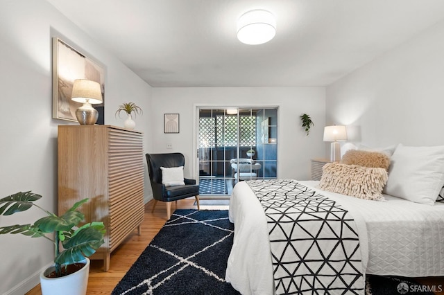 bedroom featuring wood finished floors, access to exterior, and baseboards