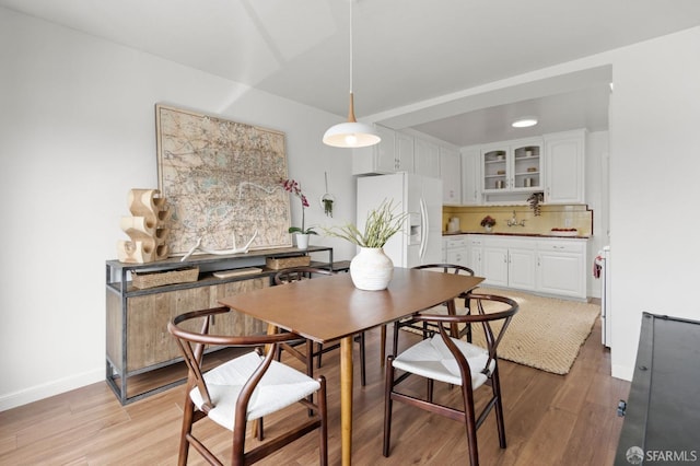 dining space with baseboards and light wood-style floors
