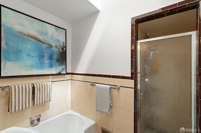 full bath featuring a garden tub, a shower stall, wainscoting, and tile walls