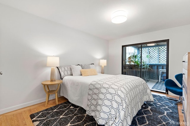 bedroom with wood finished floors, access to exterior, and baseboards