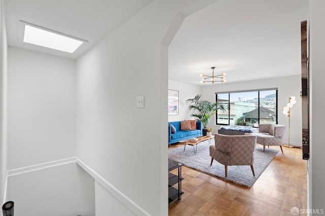 living area with arched walkways, a skylight, a chandelier, and baseboards