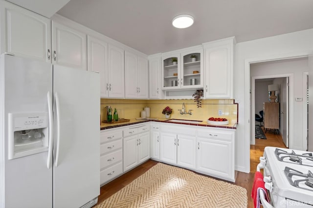 kitchen featuring white cabinetry, tasteful backsplash, glass insert cabinets, a sink, and white appliances