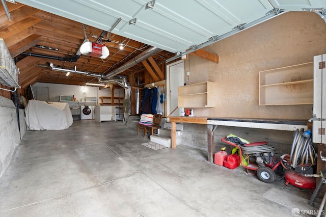 garage featuring a workshop area, a garage door opener, and independent washer and dryer