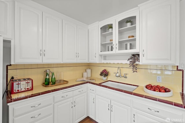 kitchen with white cabinetry, decorative backsplash, and a sink