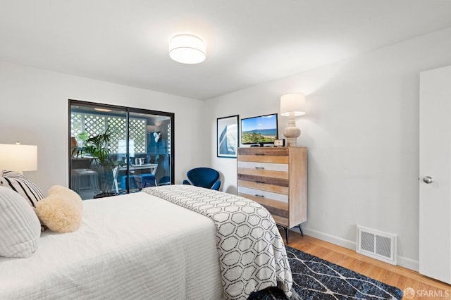 bedroom featuring wood finished floors, visible vents, access to exterior, and baseboards