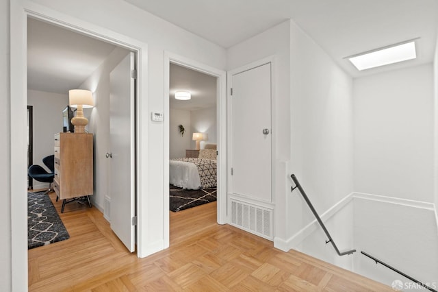 corridor featuring parquet floors, an upstairs landing, visible vents, and baseboards