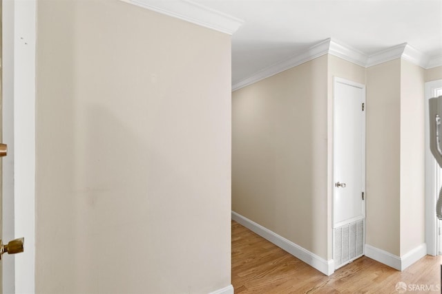 hall featuring light wood-style floors, baseboards, and ornamental molding
