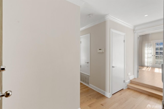 hallway featuring light wood-type flooring, baseboards, and crown molding