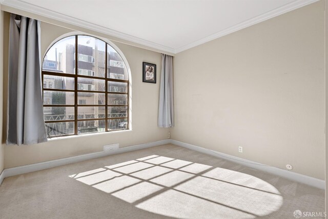 carpeted spare room featuring crown molding and baseboards