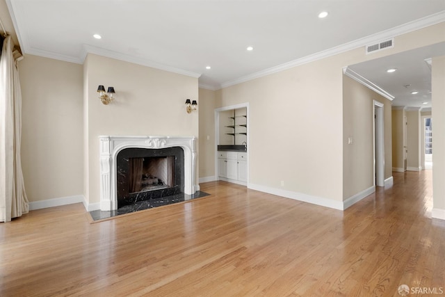 unfurnished living room with light wood-style flooring, a fireplace, visible vents, and baseboards