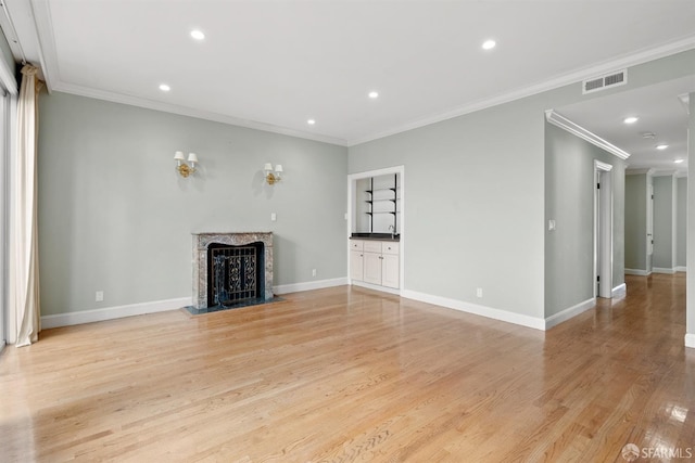unfurnished living room with visible vents, baseboards, light wood-style flooring, a premium fireplace, and recessed lighting