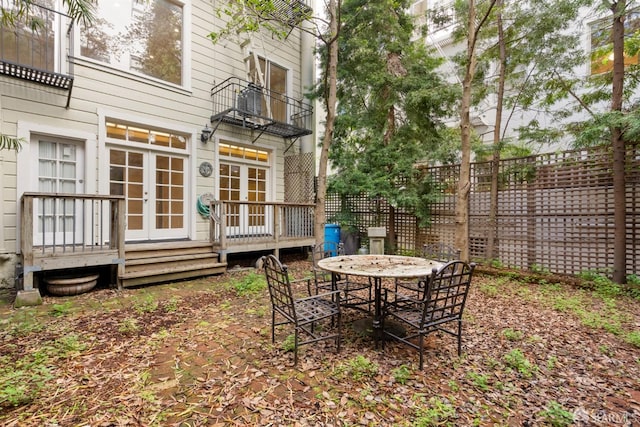 view of yard with a balcony, fence, and french doors