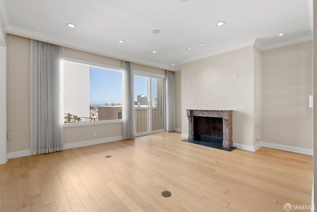 unfurnished living room with baseboards, light wood-type flooring, a high end fireplace, and crown molding