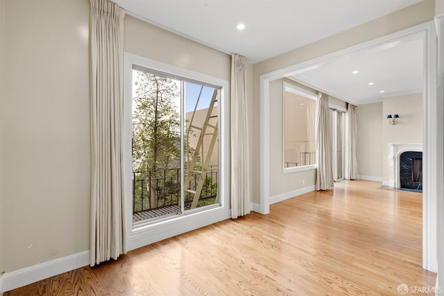 entryway with light wood finished floors, a fireplace with flush hearth, baseboards, and recessed lighting