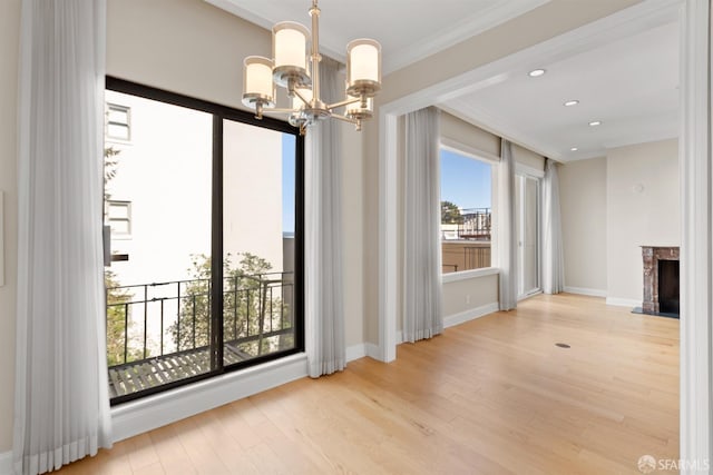 unfurnished dining area featuring recessed lighting, a fireplace, an inviting chandelier, and wood finished floors