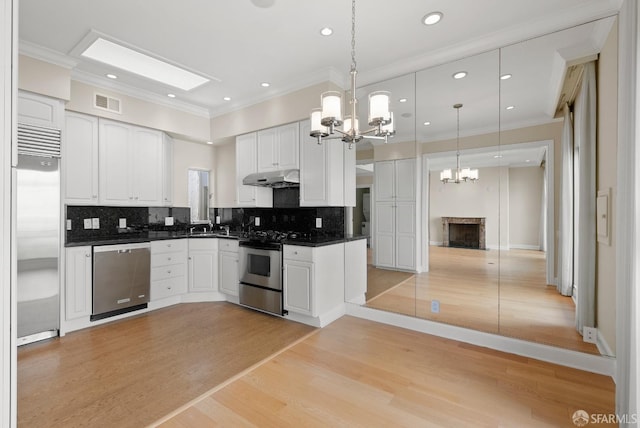 kitchen featuring dark countertops, under cabinet range hood, appliances with stainless steel finishes, and light wood-style floors