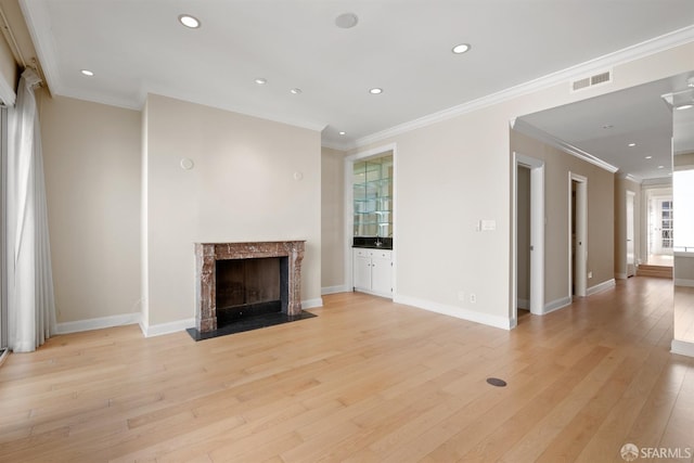unfurnished living room featuring light wood-style floors, baseboards, visible vents, and a high end fireplace