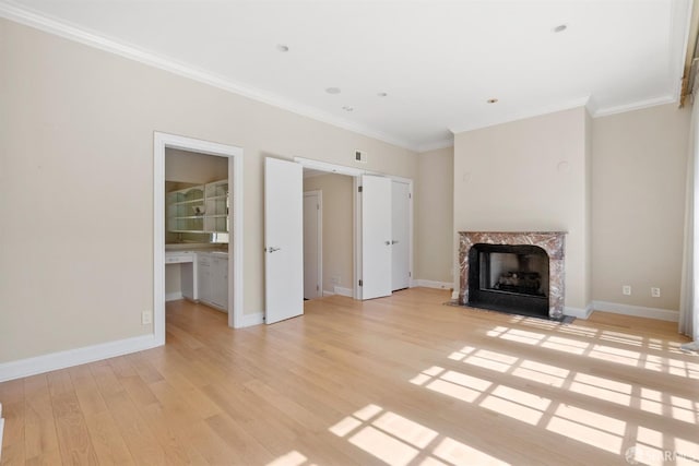 unfurnished living room with ornamental molding, a fireplace, light wood-style flooring, and baseboards