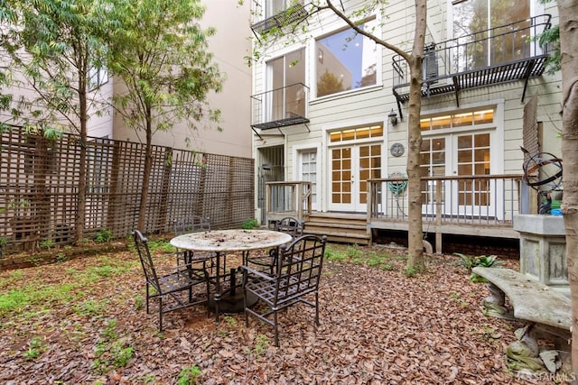 back of property featuring outdoor dining space, fence, and french doors