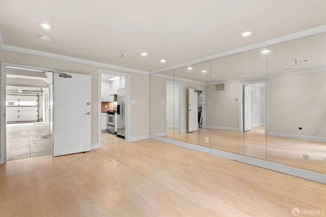 spare room with visible vents, crown molding, light wood-style flooring, and baseboards
