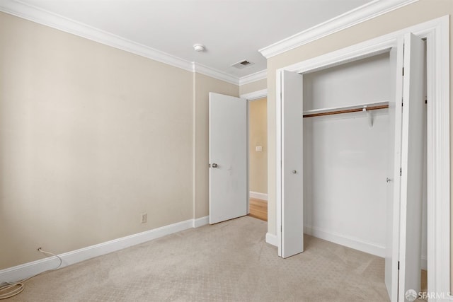 unfurnished bedroom featuring light colored carpet, visible vents, baseboards, a closet, and crown molding