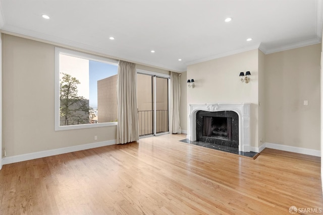 unfurnished living room with recessed lighting, a premium fireplace, wood finished floors, baseboards, and crown molding