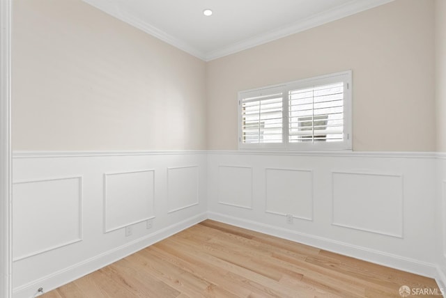 spare room with ornamental molding, light wood finished floors, a wainscoted wall, and a decorative wall