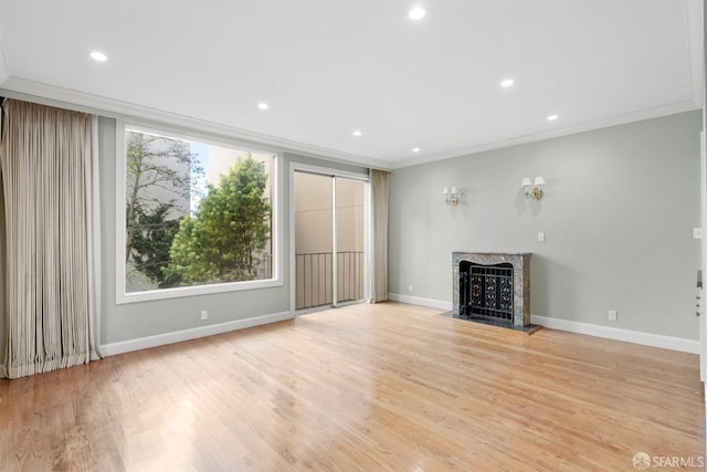 unfurnished living room with crown molding, recessed lighting, light wood-style flooring, a fireplace with flush hearth, and baseboards