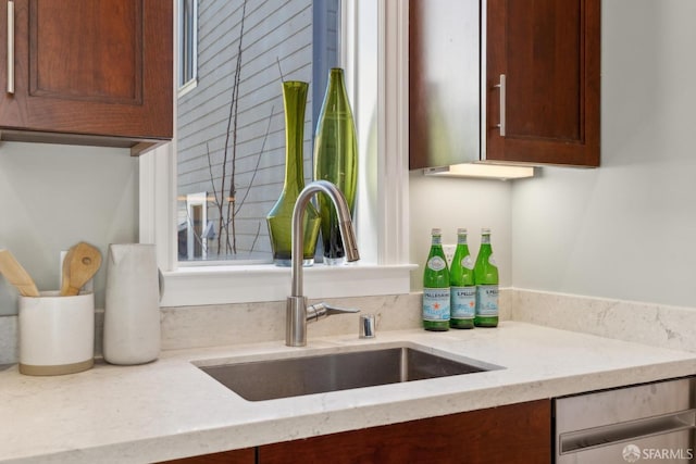 interior details featuring dishwasher, light stone countertops, and a sink