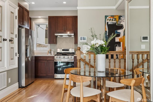 kitchen featuring light wood finished floors, under cabinet range hood, appliances with stainless steel finishes, crown molding, and light countertops