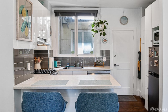 kitchen featuring dark hardwood / wood-style flooring, sink, white cabinetry, decorative backsplash, and stainless steel appliances