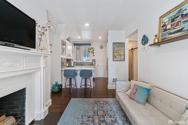 living room featuring a premium fireplace, a barn door, and dark hardwood / wood-style floors