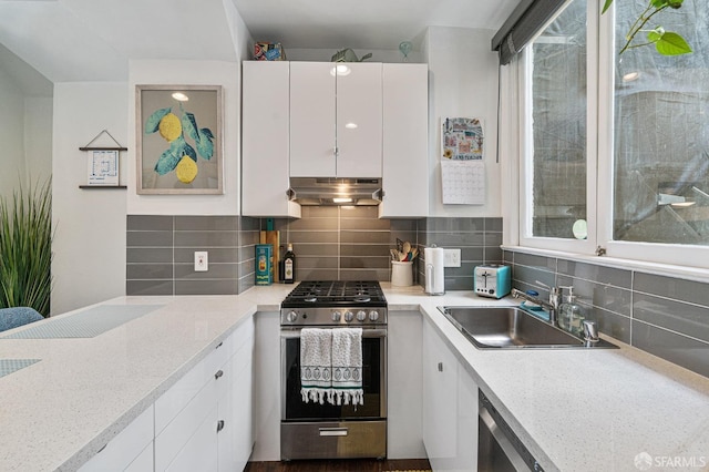 kitchen featuring white cabinets, tasteful backsplash, sink, stainless steel gas range oven, and light stone counters