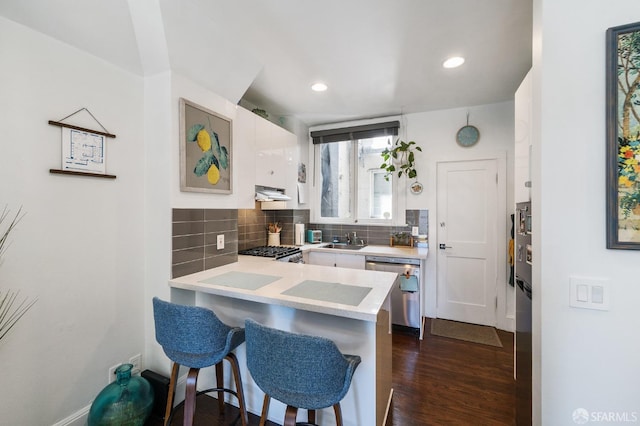 kitchen featuring dishwasher, decorative backsplash, a kitchen breakfast bar, sink, and white cabinets